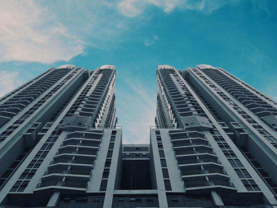 Free Image of Two Tall Buildings With Balconies Against a Blue Sky 