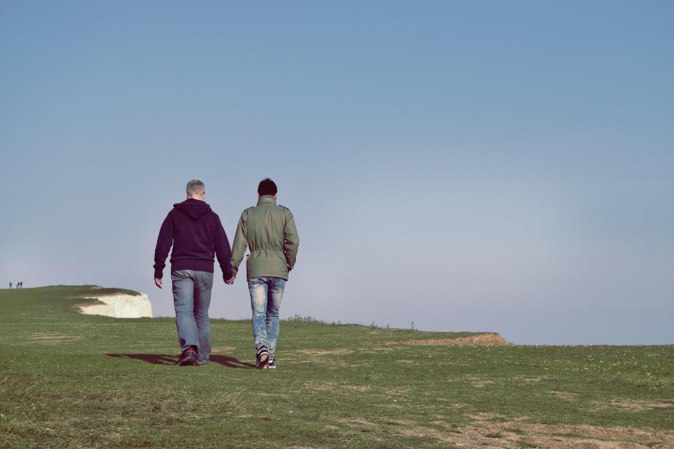 Free Image of Two Men Walking Across a Lush Green Field 