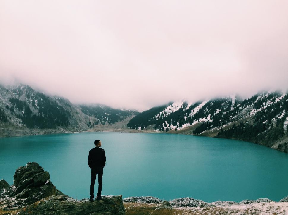 Free Image of Man Standing on Mountain Beside Lake 