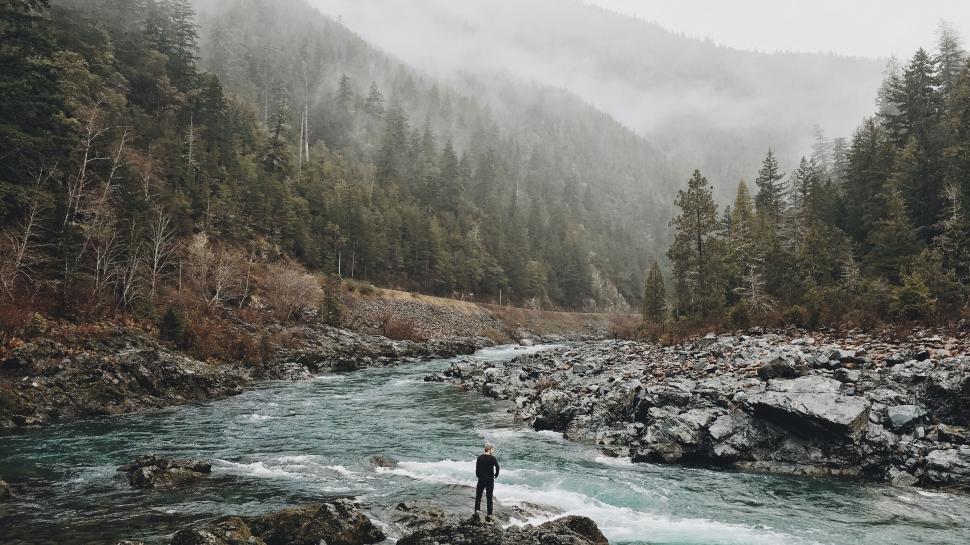 Free Image of Man Standing on Rock by River 