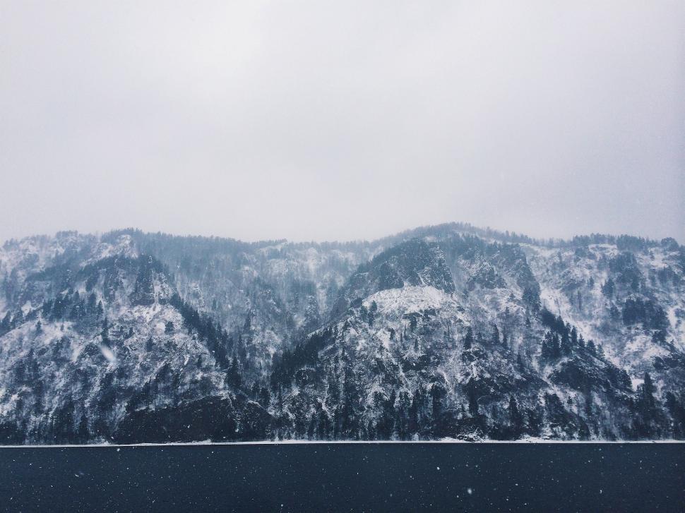Free Image of Snow-Covered Mountain Next to Body of Water 
