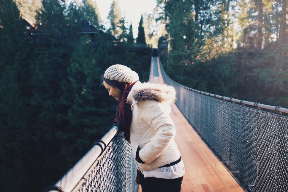 Free Image of Woman Standing on Bridge With Trees in Background 