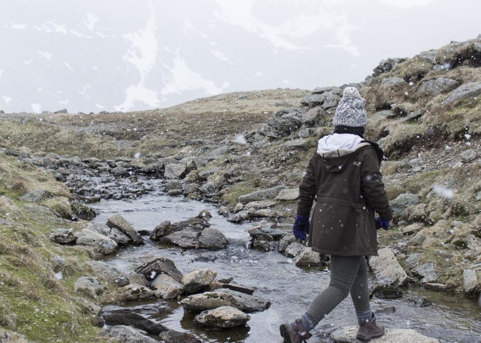 Free Image of Person Walking Across Stream in the Mountains 