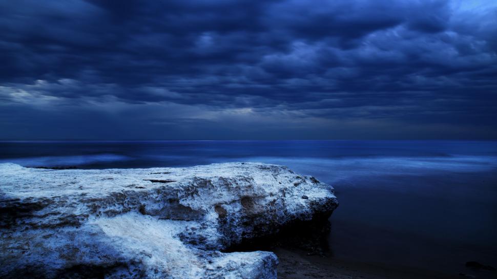 Free Image of Large Rock on Beach Under Cloudy Sky 