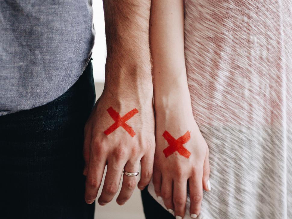 Free Image of Couple Holding Hands With Red Crosses Painted on Them 