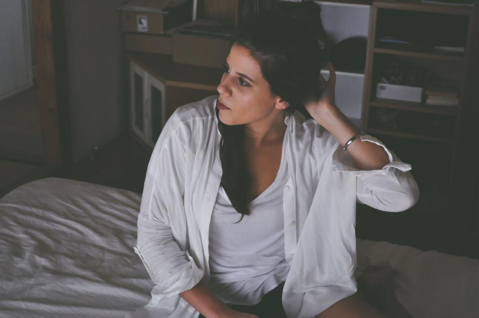 Free Image of Woman Sitting on Bed in Room 