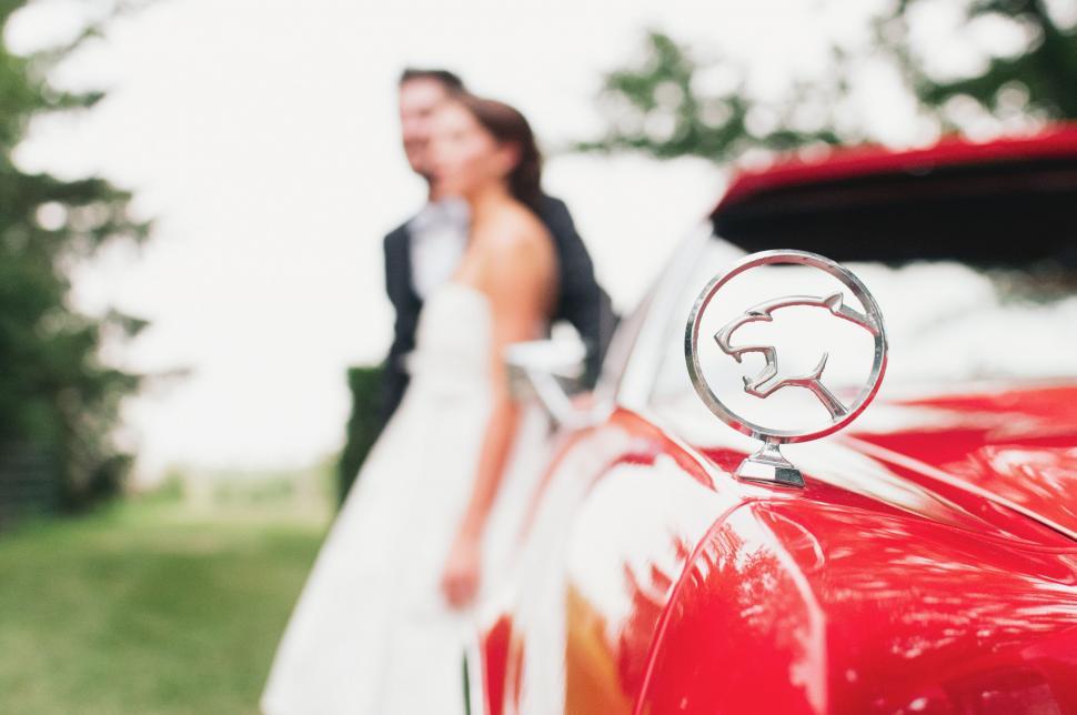 Free Image of Bride and Groom Standing Next to Red Car 