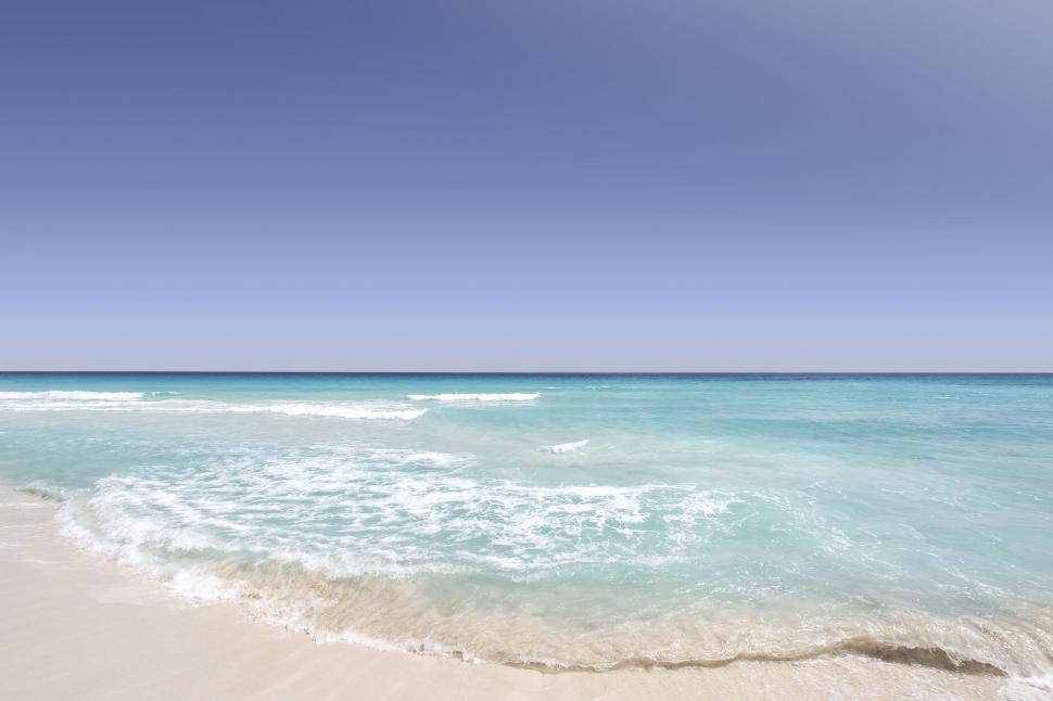 Free Image of Sandy Beach With Blue Water and White Sand 