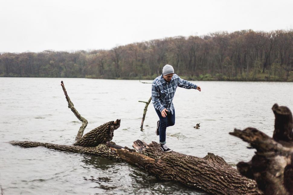 Free Image of Man Standing on Top of Log in Water 