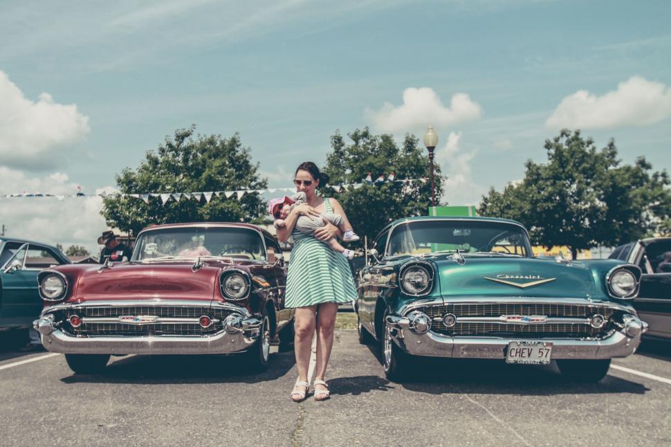 Free Image of Woman Standing in Front of Classic Cars 