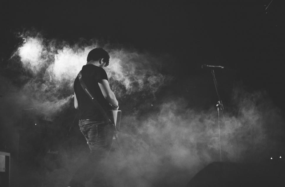 Free Image of Man Standing on Top of Stage Surrounded by Smoke 