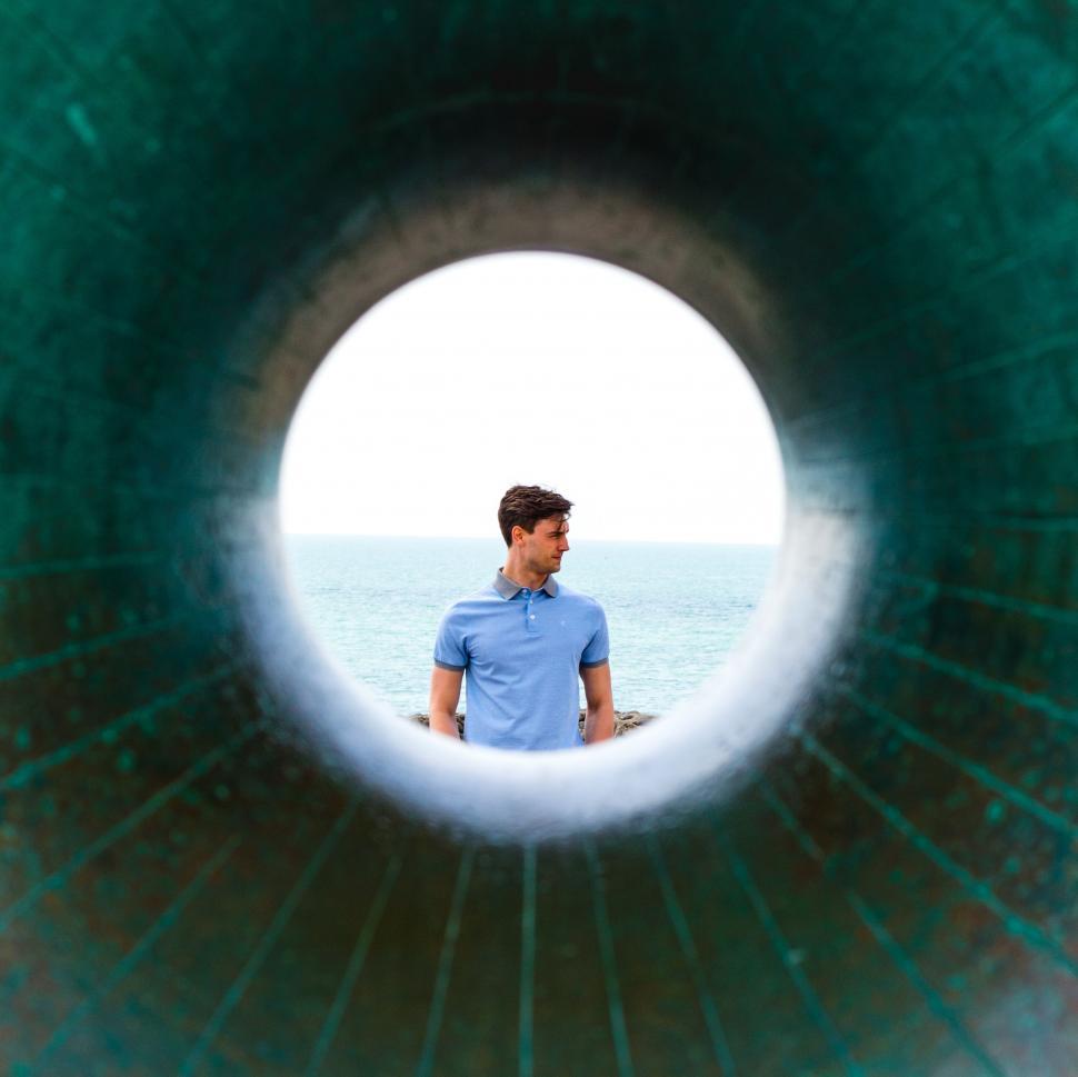 Free Image of Man Standing in Tunnel Looking Out at Ocean 