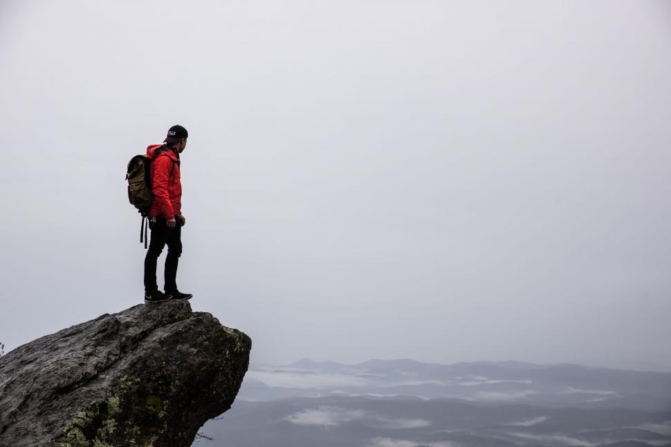 Free Image of Man Standing on Top of a Mountain With a Backpack 