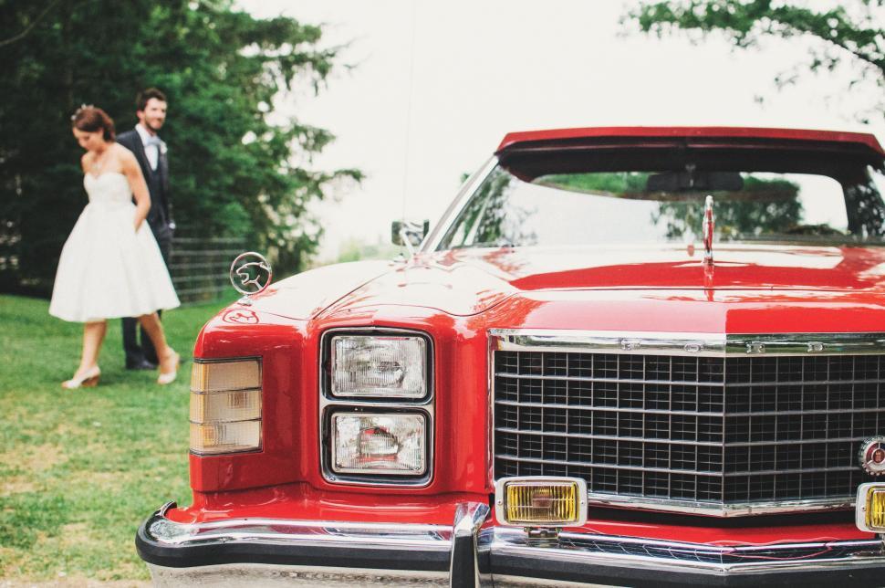 Free Image of Bride and Groom Standing Next to Red Car 