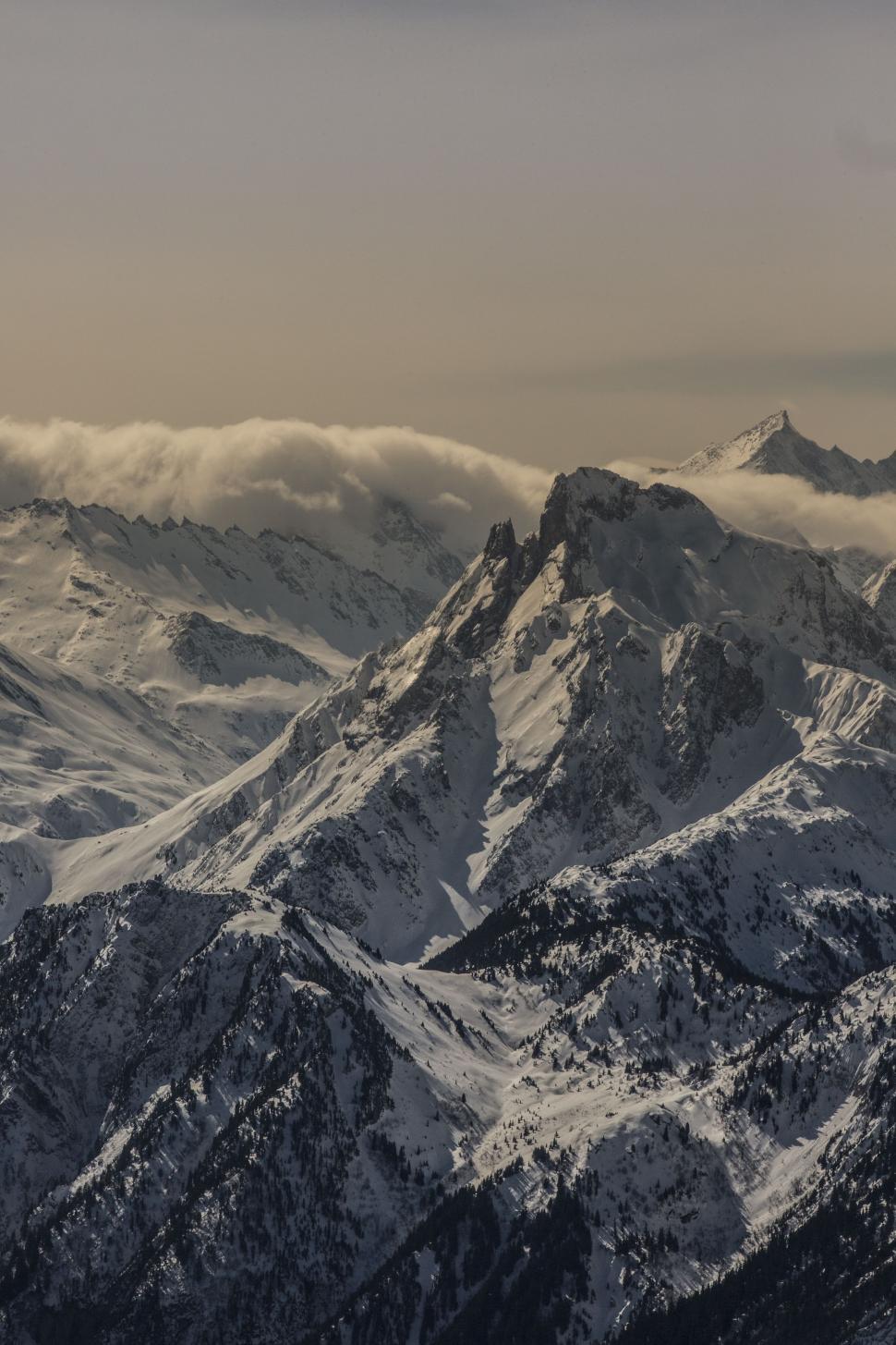 Free Image of Snow-Covered Mountain Range Under Cloudy Sky 