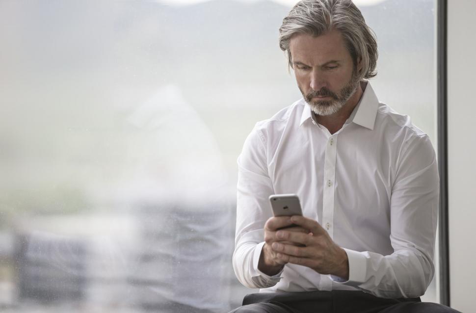 Free Image of Man Sitting Down Looking at Cell Phone 