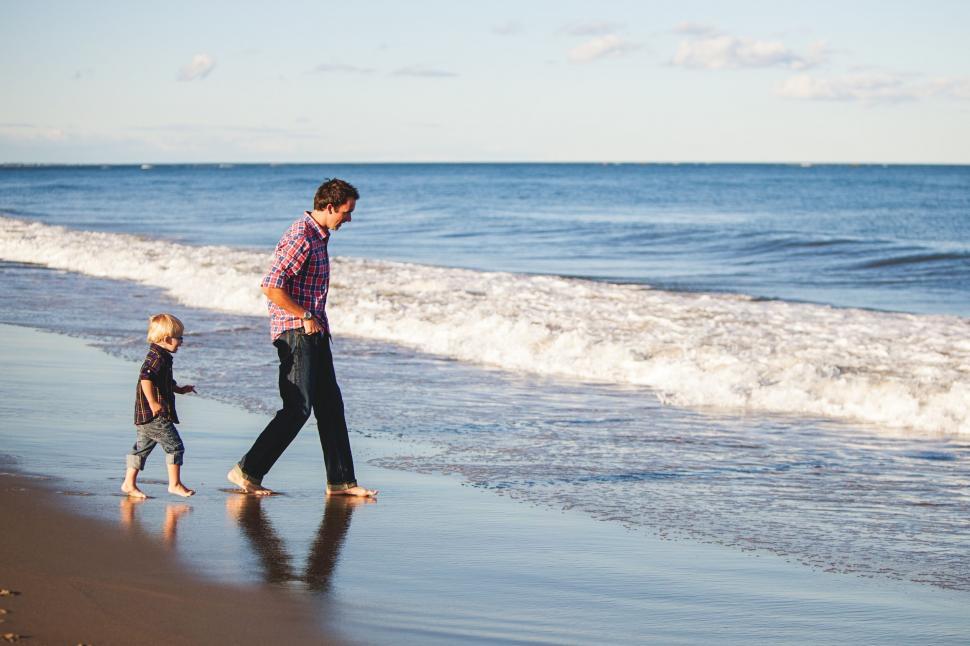 Free Image of Man and Child Walking on Beach 