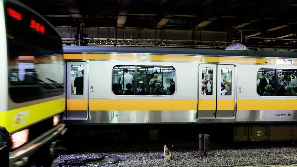 Free Image of Silver and Yellow Train Traveling Through Train Station 