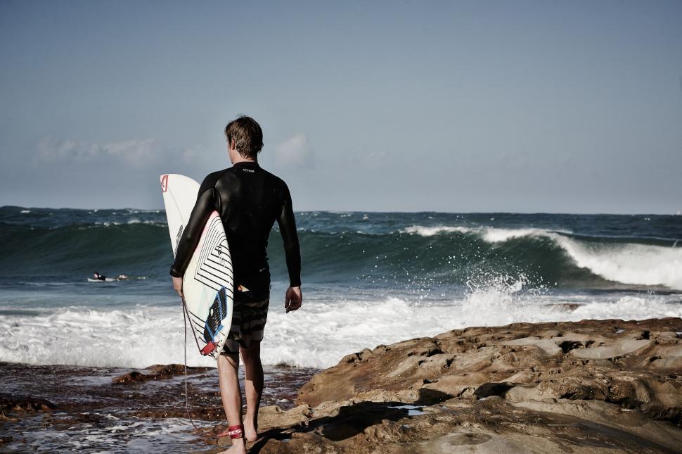 Free Image of Man Holding Surfboard on Rocky Beach 