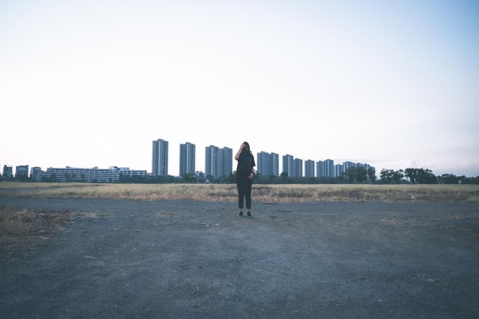 Free Image of Person Standing in Field With Tall Buildings in Background 