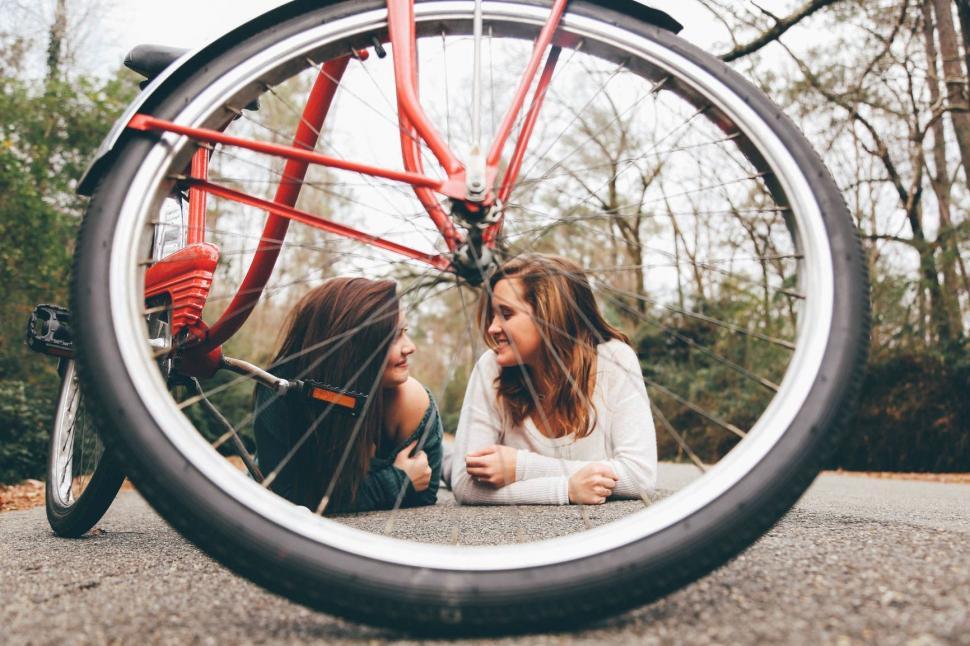 Free Image of Two Women Sitting Next to a Red Bike 