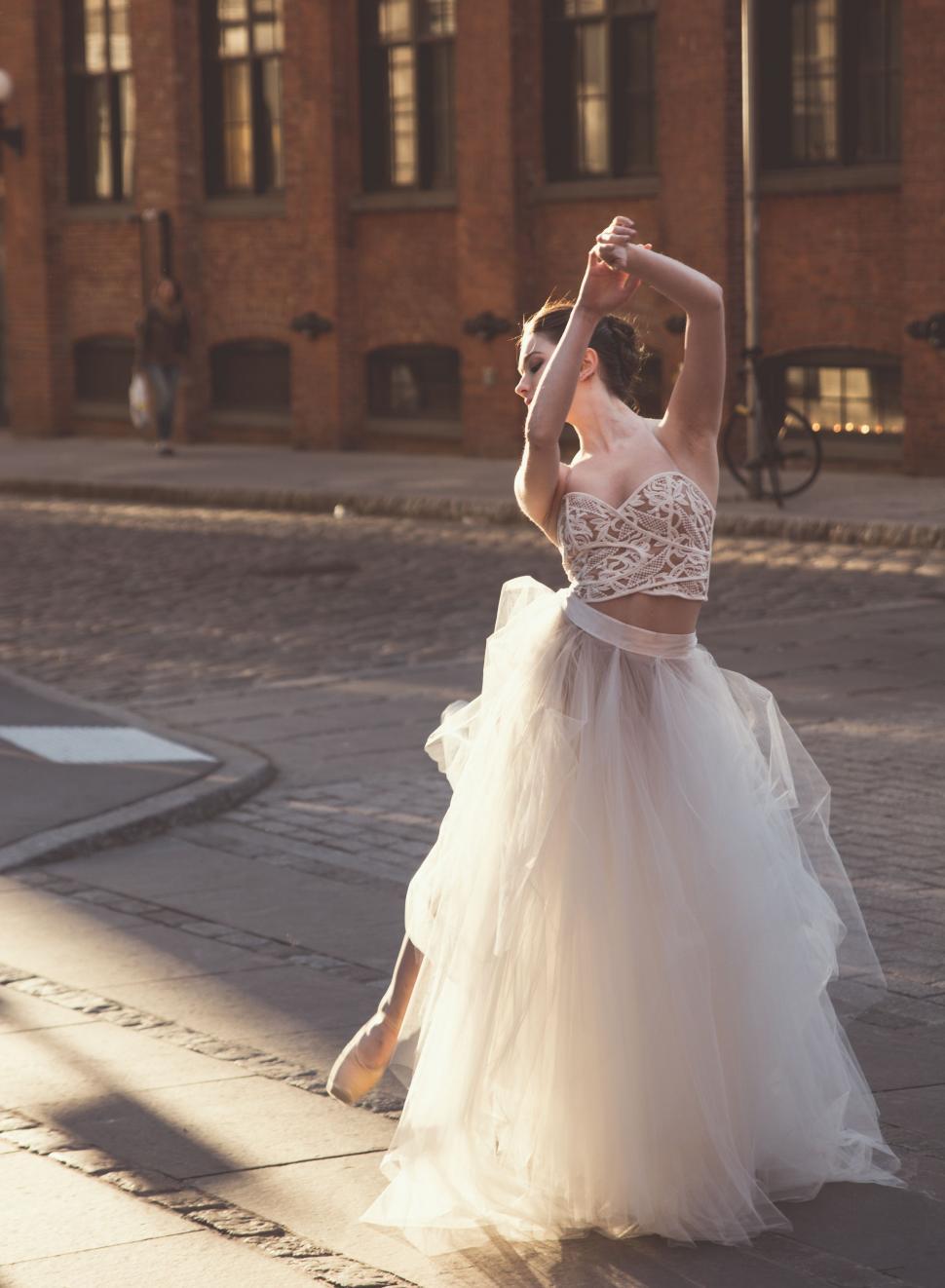 Free Image of Woman in White Dress Dancing on Street 