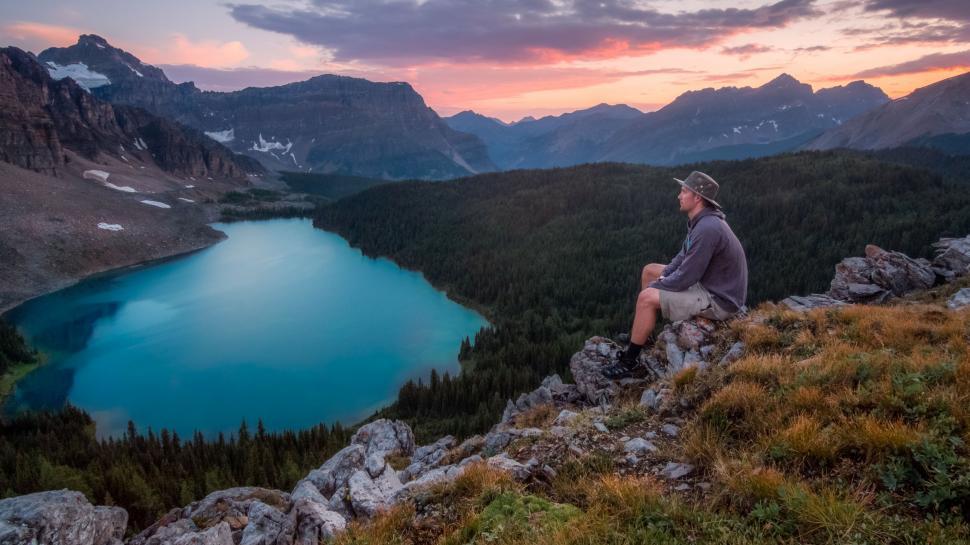 Free Image of Man Sitting on Top of a Mountain by Lake 