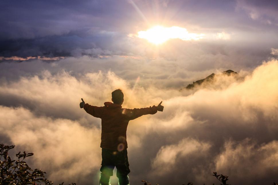 Free Image of Man Standing on Mountain Top Surrounded by Clouds 
