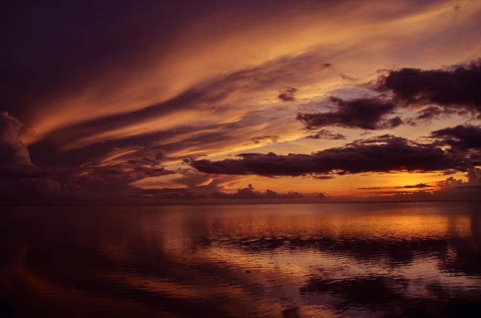 Free Image of Sunset Over a Body of Water With Clouds in the Sky 
