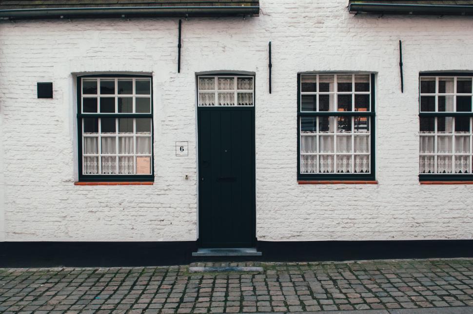 Free Image of White Brick Building With Three Windows and Black Door 