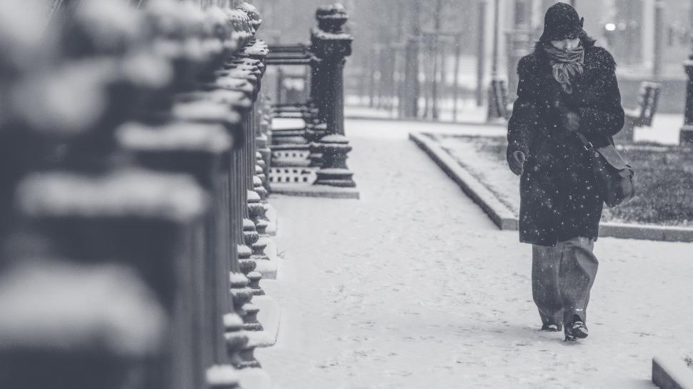 Free Image of Woman Walking Down Sidewalk in Snow 