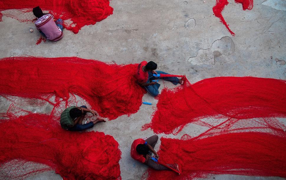 Free Image of Group of People Laying on Ground Covered in Red Yarn 