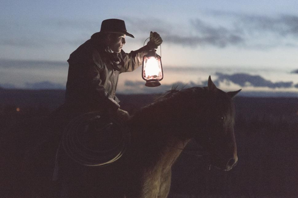 Free Image of Man Riding on Horse Holding Lantern 