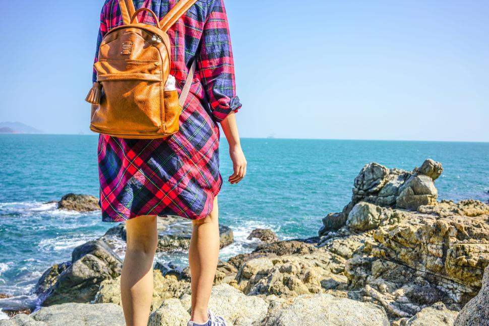 Free Image of Person With Backpack Standing on Rock by Ocean 