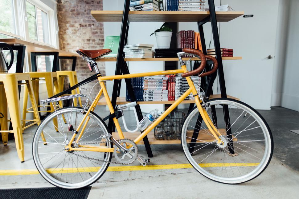 Free Image of Yellow Bicycle Parked in Front of Bookshelf 
