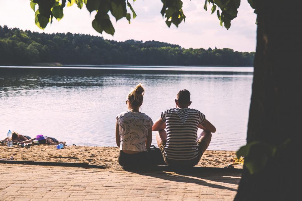 Free Image of Couple Sitting on Beach Near Water 