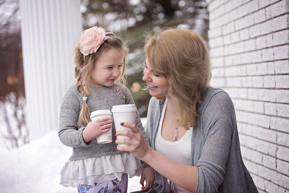 Free Image of Woman Holding Cup of Coffee Next to Little Girl 