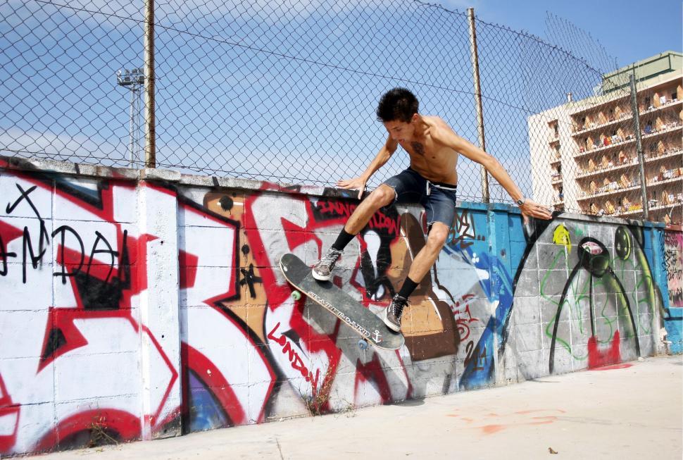 Free Image of Man Riding Skateboard Up Graffiti Covered Wall 