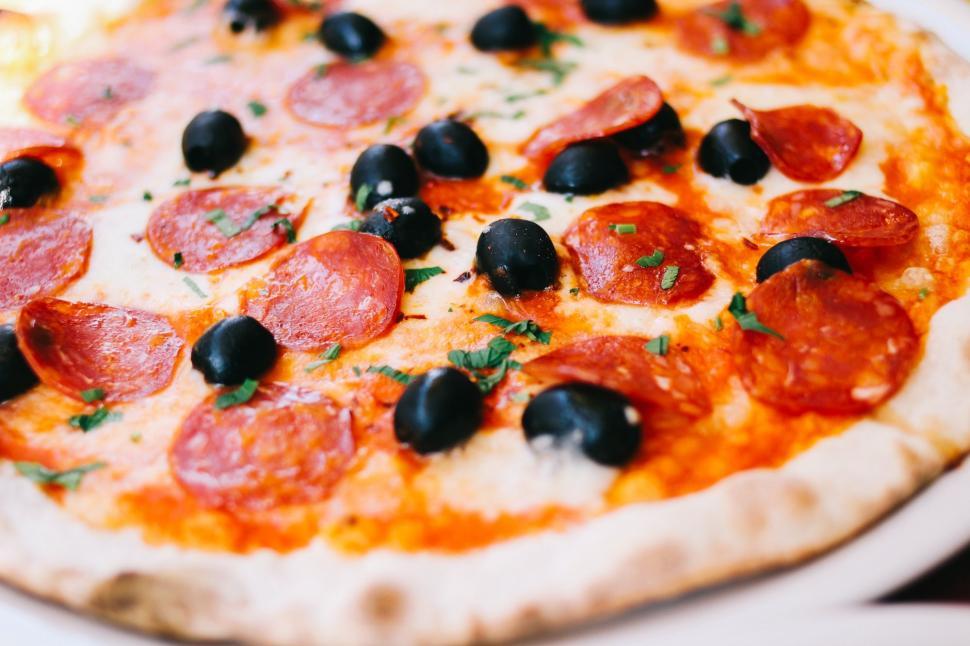 Free Image of Pepperoni and Black Olive Pizza on a White Plate 