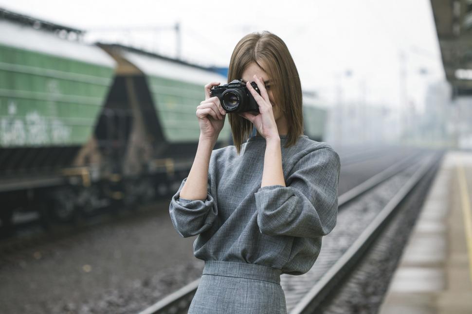 Free Image of Woman Taking Picture of Train on Train Track 