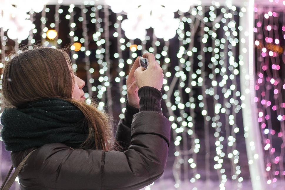 Free Image of Woman Taking Picture of Display of Lights 
