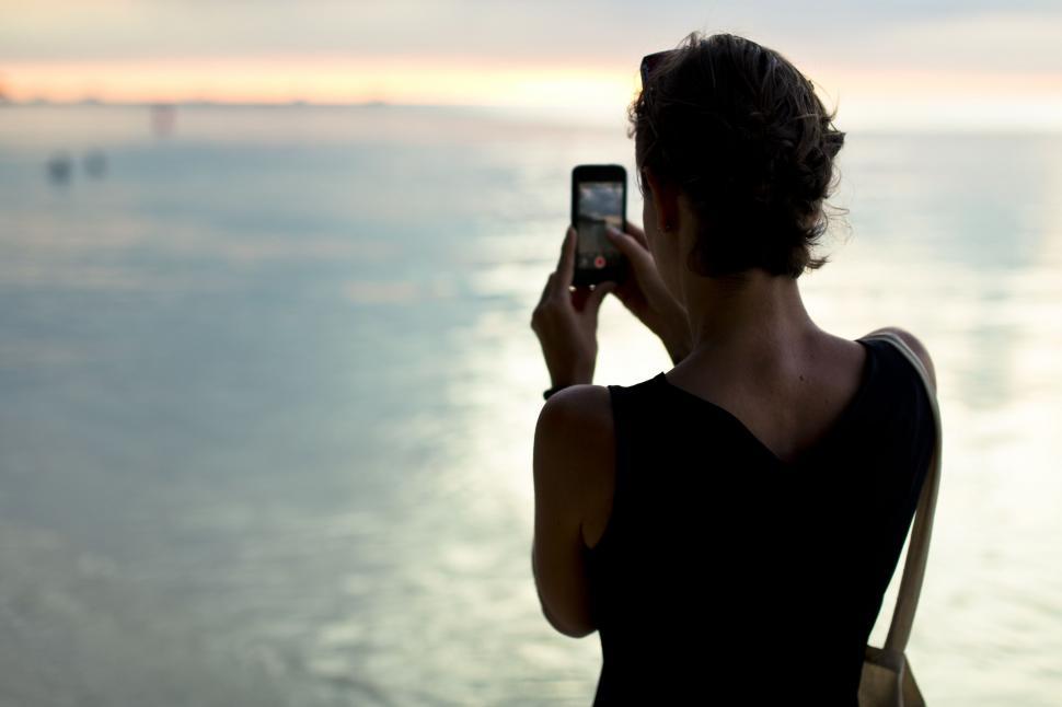 Free Image of Woman Taking a Picture of the Ocean With Cell Phone 