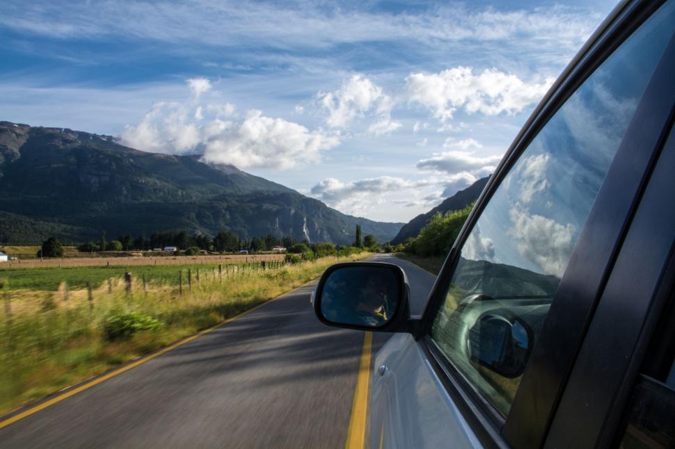 Free Image of Car Driving Down Road With Mountains in Background 