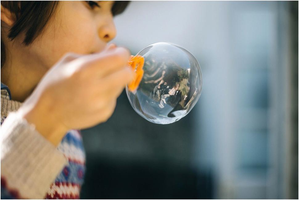 Free Image of Woman Blowing Bubble With Orange in Mouth 