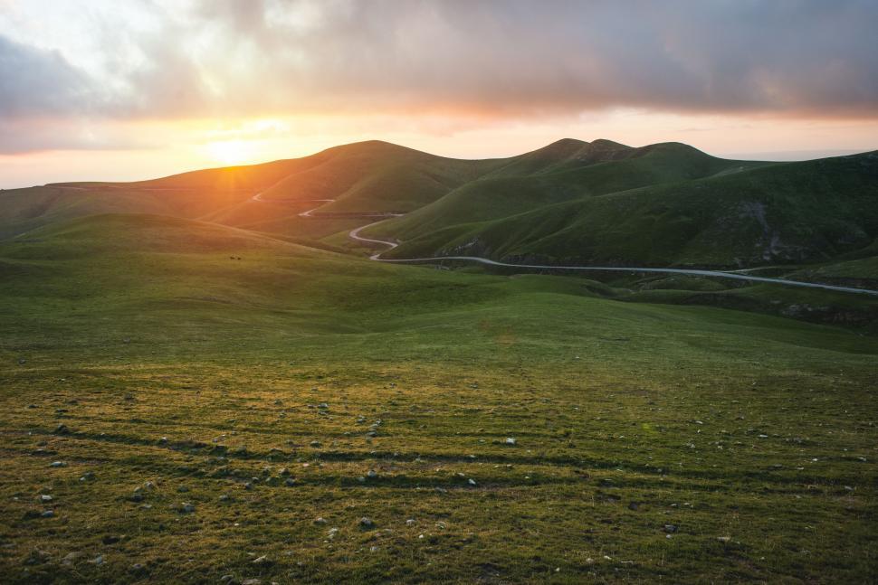 Free Image of Sun Setting Over Grassy Hill 