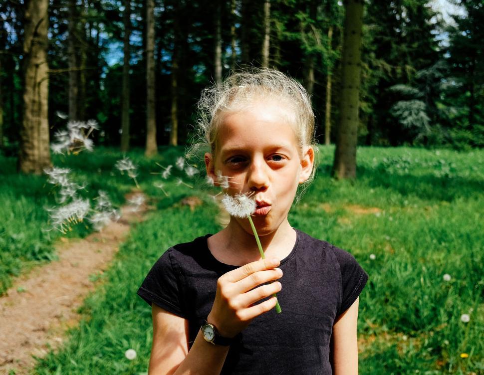 Free Image of Young Girl Blowing Dandelion in Forest 