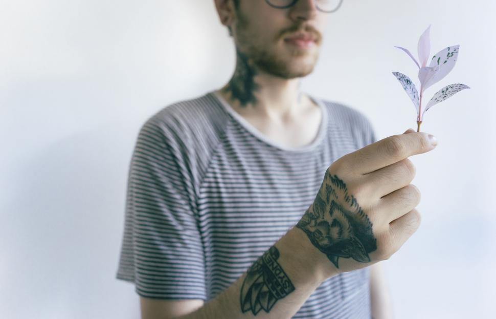 Free Image of Man Holding Small Plant With Tattoo 