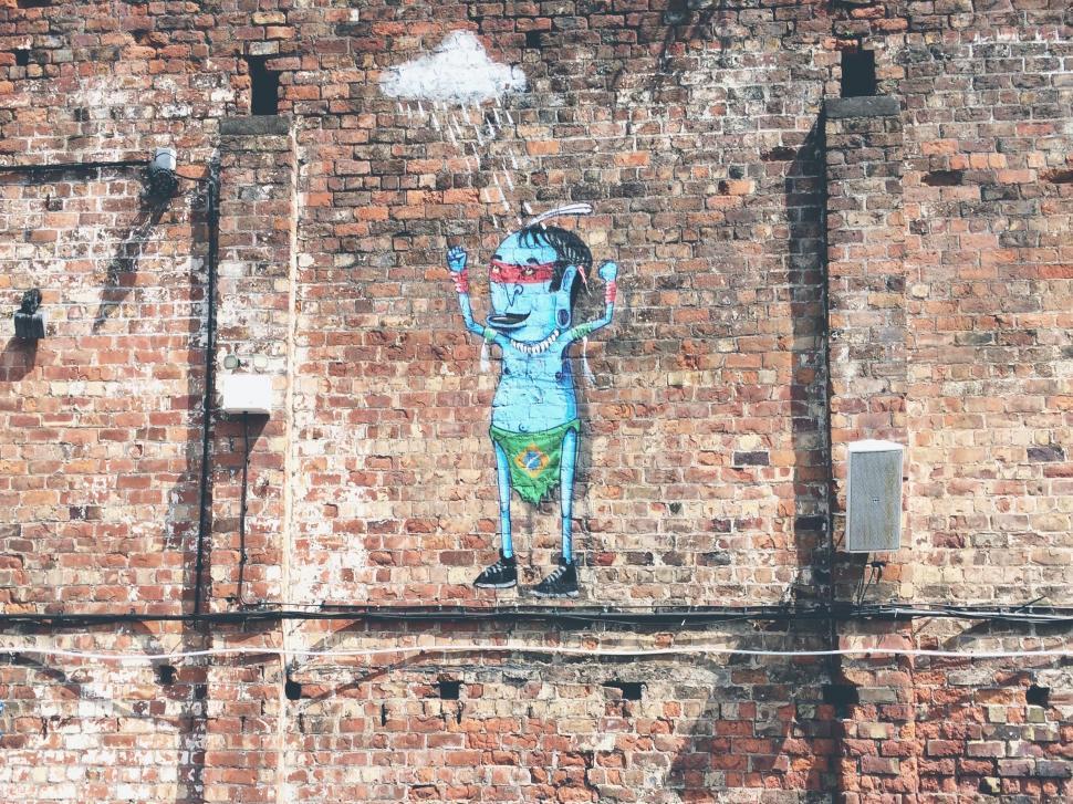 Free Image of Brick Wall With Painting of Person Holding Frisbee 