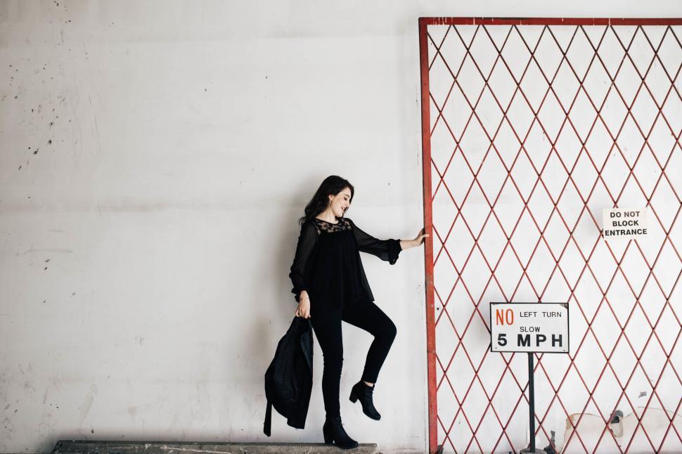Free Image of Woman Standing by Gate Holding Bag 
