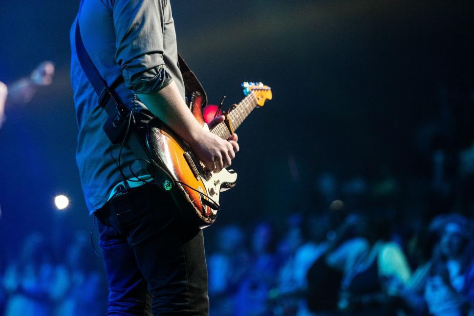 Free Image of Man Standing on Stage With Guitar 